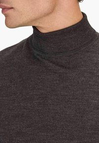 Mörkgrå polotröja med ribbat mönster och figurnära passform. Tyget verkar mjukt och elastiskt med ett högt halsöppning.