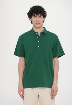 Green polo shirt with a classic design, short sleeves, and a three-button placket, made from a solid, textured fabric.