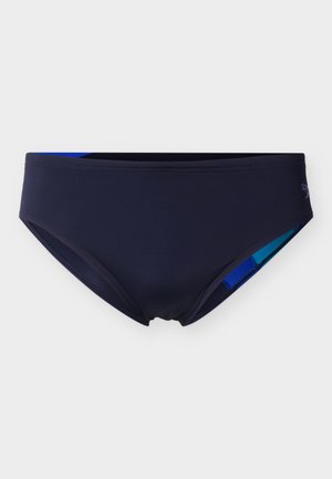 Meeste tumesinised ujumispüksid madala vöökohaga, millel on ümber vöökohja ja säärte avades nähtav peen sinine ääris.