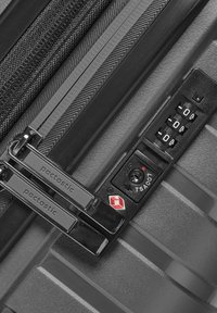 Valise rigide noire avec surface texturée, dotée de doubles zips et d'une serrure à combinaison approuvée par la TSA. Logo visible sur les zips.