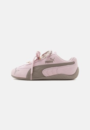 Baskets Puma rose clair avec semelle grise, logo Puma sur le côté et lacets noués vus de côté extérieur sur fond blanc.
