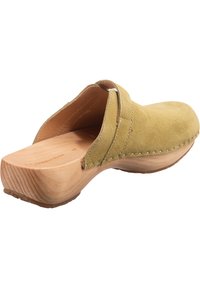 Träklack i mjukt gult mocka med en träbotten, med sydda detaljer och öppen baksida. Slät textur på ovansidan.