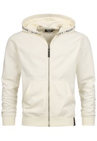 Crème kleurige zip-up hoodie van zachte stof. Voorzien van een trekkoord kap met bedrukte logo, voorzakken en geribbelde manchetten. Subtiele branding op de borst.