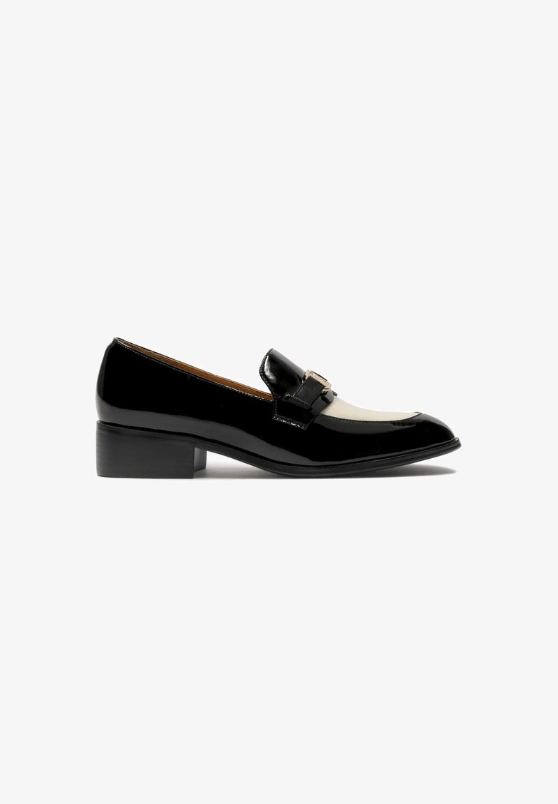Mocassino in pelle verniciata nera con punta squadrata, pannello accentato crema, tacco basso e fascia decorativa con dettaglio di fibbia metallica.