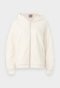 Krémová mikina na zips vyrobená z jemného materiálu, ktorá má kapucňu, rebrované manžety a klokanie vrecká. Na hrudi je vyšité logo "MM".