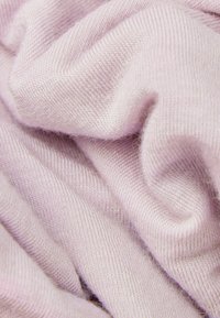 Tela de punto suave de color rosa claro con una fina textura acanalada, mostrada en primer plano con pliegues y arrugas suaves.