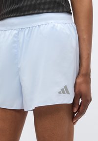 Shorts de sport bleu clair en tissu lisse, avec un logo Adidas gris sur l'ourlet et une taille élastique pour un maintien sûr.