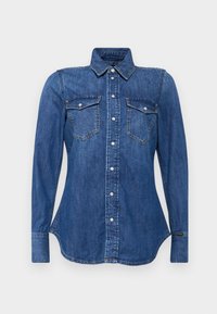 Camicia di denim blu medio con colletto ampio, maniche lunghe, due tasche sul petto e bottoni a pressione argentati. Orlo curvo.