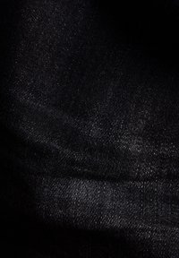 Tela de mezclilla negra con una superficie texturizada, que presenta variaciones sutiles en el tono y un acabado suave. La vista en primer plano resalta los detalles del tejido.