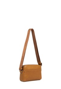 Borsa a tracolla in pelle tan con una texture liscia, forma rettangolare e tracolla regolabile con logo "LANCASTER". Accenti in metallo visibili.