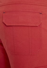 Roter Stoff mit glatter Textur, ausgestattet mit einer rechteckigen Gesäßtasche und sichtbaren Steppnähten. Gerade Schnittlinien betonen das Design.