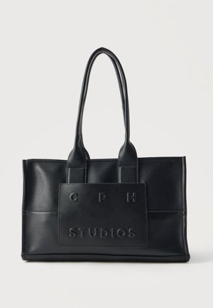 Bolso de mano rectangular de cuero negro con dos asas largas y un parche frontal con letras en relieve ""CPH STUDIOS"".