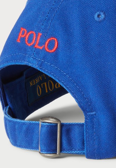 Casquette de baseball en coton bleu avec broderie rouge "POLO", boucle en métal argenté réglable et tissu texturé sur la visière et la sangle.