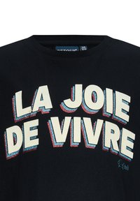 Zwart T-shirt met korte mouwen featuring gedurfde, gelaagde tekst "LA JOIE DE VIVRE" in crème met blauwe en rode accenten. Gemaakt van katoen met een ronde hals.