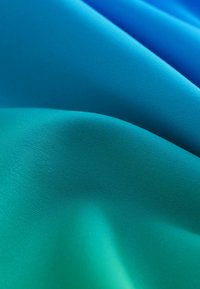 Tekstil med struktur i gradient nuancer af teal og blå, glat tekstur med en let glans, der har bløde, flydende kurver.
