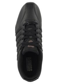 Baskets en cuir noir avec une texture lisse, dotées de six œillets pour les lacets, d'un logo en relief et de trois bandes horizontales sur les côtés.