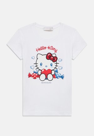 Biele bavlnené tričko s flitrovou grafikou Hello Kitty držiacej červené srdce, obklopené červenými a modrými cukríkmi a srdiečkami.