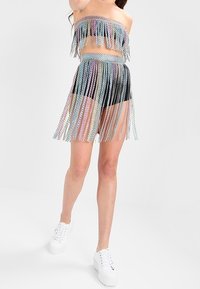 Conjunto de dos piezas que incluye un top sin tirantes y una falda a juego con detalles de flecos multicolores. Fabricado en un material brillante y texturizado.