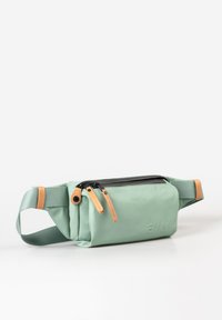 Grüner Stoff-Hüftbeutel mit einem schwarzen Reißverschluss, beige Lederakzenten und einer strukturierten Oberfläche. Seitenriemen zum Tragen und mit Logo auf der Vorderseite geprägt.