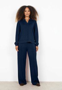 Conjunto de ropa de descanso en azul marino que incluye una camiseta de manga larga con cuello y pantalones de pierna ancha, confeccionado con una tela suave y un diseño relajado.