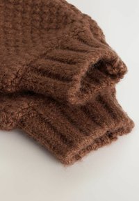 Bruna stickade handskar med ett texturerat, ribbat mönster. Tillverkade av mjukt, luddigt tyg och har en vikbar manschettdesign.