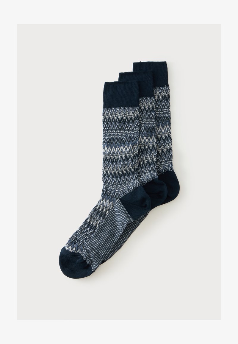 Trois paires de chaussettes mi-mollet avec des bouts, talons et bordures bleu marine et un motif en zigzag tricoté en tons de bleu, blanc et gris.