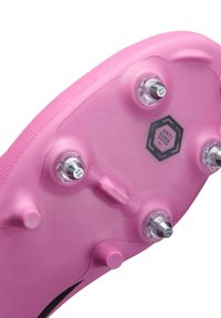 Rosa fotbollsskor med sula som har metallspikar, "ANTI CLOG" branding och texturerad yta; designad för grepp och stabilitet på planen.