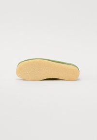 Chaussures vertes avec une tige texturée et douce et une semelle en caoutchouc beige clair. Forme profilée conçue pour le confort et le soutien.