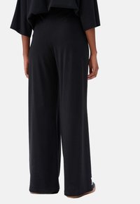 Zwarte wijde pantalons van een soft, gladde stof, met een hoge taille en een losse pasvorm, voor comfort en elegantie.