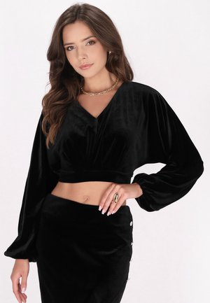 Haut court en velours noir avec un décolleté en V et des manches ballon, assorti d'une jupe taille haute à boutons décoratifs.