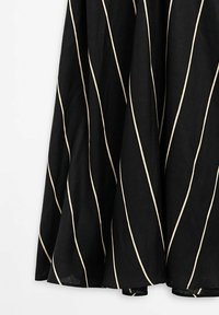 Jupe noire avec des rayures diagonales crème, fabriquée en tissu léger. L'ourlet est légèrement évasé, ce qui améliore le design global.