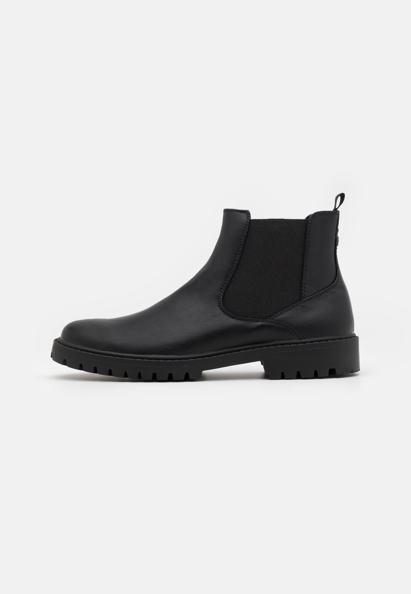Bottines Chelsea en cuir noir avec des panneaux élastiques sur les côtés, une sangle de traction et une semelle robuste avec un profil cranté. Texture lisse avec un minimum de détails.