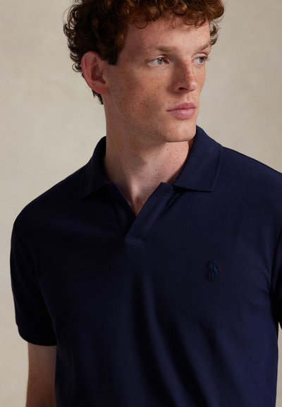 Navy polo shirt in textured fabric with a collared neck, short sleeves, and a small embroidered logo on the left chest.