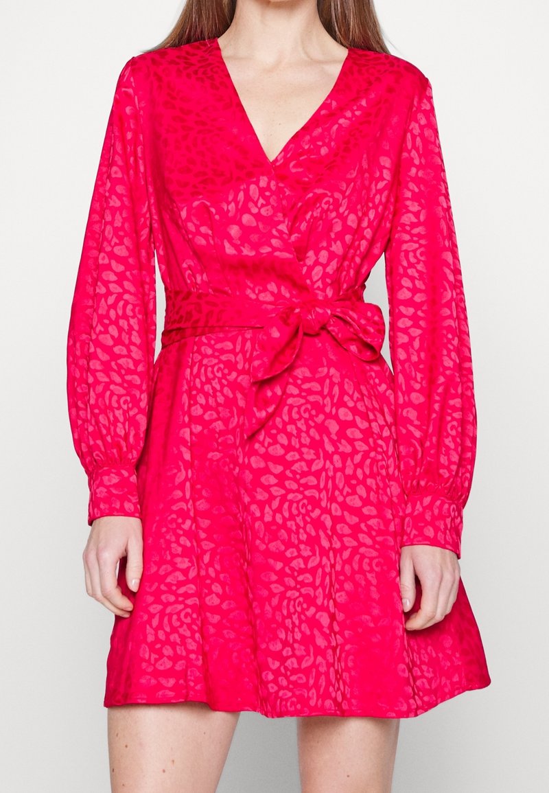 Robe fuchsia avec un décolleté en V, des manches longues bouffantes et une taille ceinturée. Présente un motif texturé à imprimé animalier et une jupe évasée.