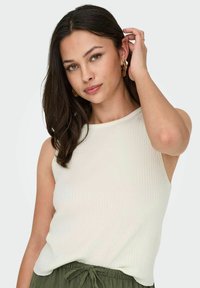 Witte geribbelde tanktop met een ronde halslijn, gecombineerd met olijfgroene broek met trekkoord. De stof heeft een zachte textuur en een getailleerde pasvorm.