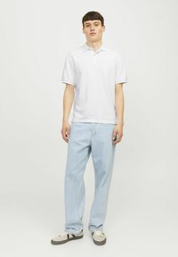 Cămașă polo albă cu guler clasic, asortată cu blugi drepti de culoare albastră deschisă și adidași gri cu accente negre. Design simplu, potrivire lejeră.