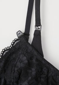 Czarny koronkowy biustonosz z motywami kwiatowymi, regulowanymi ramiączkami i zapięciem na haftkę. Tekstura łączy gładki materiał z misternymi koronkowymi detalami.