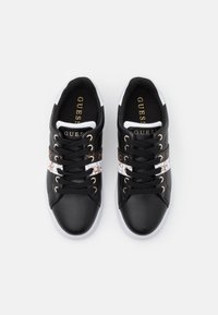 Sneaker in pelle nera con una fascia bianca e decorata, punta rotonda, lacci neri e dettagli dorati sul logo e sugli occhielli.