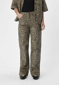 Luipaardprintpak in aardetonen; bestaat uit losse broeken en een oversized shirt, beide met een zachte textuur en zijzakken.