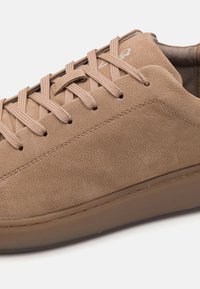 Adidași bej din suede texturat cu o talpă din cauciuc neted, având șireturi subțiri și detalii de cusătură subtile.