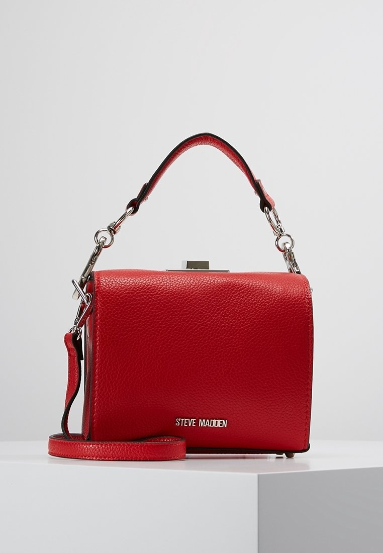Sac bandoulière en cuir rouge à finition texturée, avec une poignée courte, une sangle réglable et des ferrures argentées. Il possède une fermeture à pince supérieure.