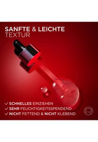 Przezroczysta buteleczka z kroplomierzem, z czarną nakrętką i srebrnymi akcentami, zawierająca jasnoczerwony serum o błyszczącej teksturze, na tle intensywnej czerwieni.