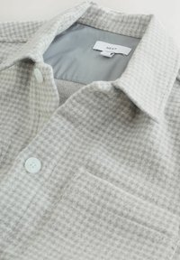 Grau-weiße karierte Button-Up-Hemd aus weichem Stoff, mit Kragen, einer Brusttasche und weißen Knöpfen.