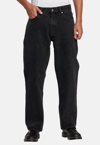 Black denim jeans with a loose fit, featuring five pockets and a button closure. The fabric has a subtle texture and minimal whiskering.