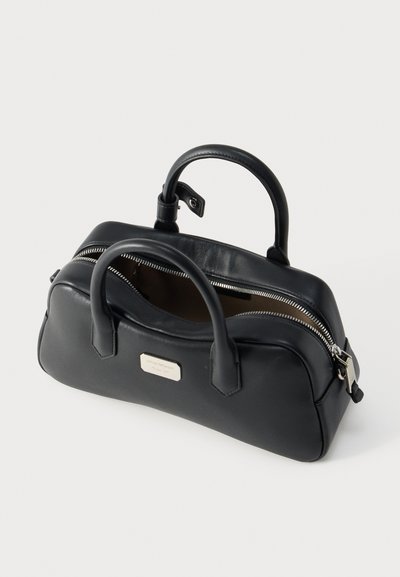 Μαύρη δερμάτινη τσάντα χειρός με δύο λαβές, ασημί φερμουάρ μερικώς ανοιχτό και μικρή ορθογώνια μεταλλική πινακίδα με το λογότυπο στην πρόσοψη.