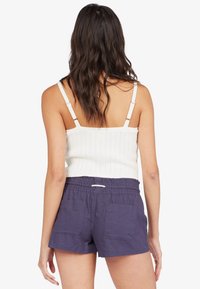Débardeur blanc côtelé avec des bretelles ajustables, associé à un short bleu marine avec une taille élastique et deux poches arrière.