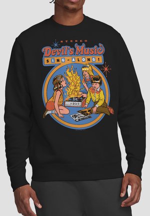 Three children sit around a flaming record player with vinyl records, text above reads "Devil's Music Sing-Along" on a black sweatshirt.