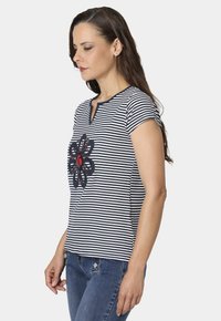 Camiseta a rayas en azul marino y blanco con mangas cortas y escote en V. Presenta un diseño de bordado floral en azul oscuro y rojo en el centro.