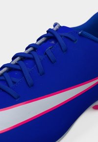 Μπλε αθλητικό παπούτσι με υφασμένο επάνω μέρος, επίπεδα κορδόνια, ασημί ρίγα και ροζ λεπτομέρειες στη σόλα και στο σχέδιο.