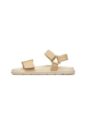Sandalo flat beige con due cinturini regolabili con parti in metallo dorato, suola imbottita e design con punta aperta.